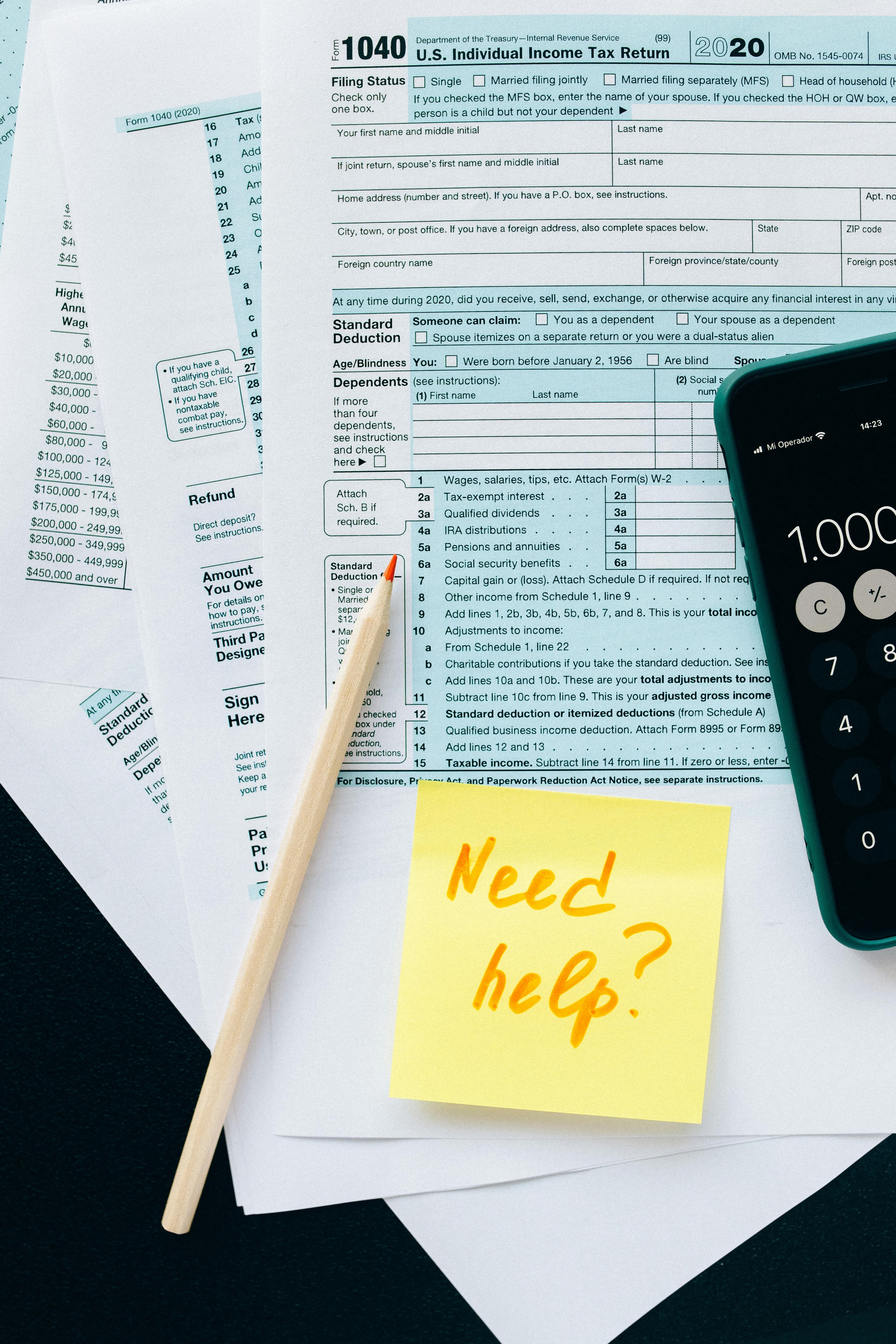 Tax forms with Need Help sticky note and calculator